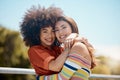 Portrait of two young mixed race female friends embracing each other and smiling outside on a sunny day. A Beautiful gay Royalty Free Stock Photo