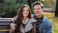 Portrait of two young partners couple in romantic relations caucasian family flirting sit on bench handsome guy kiss Royalty Free Stock Photo