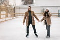 Two young people holding their hands in figure skating field heaving fun