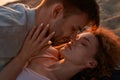 Portrait of two young people in love kissing while lying together on the beach at sunset Royalty Free Stock Photo