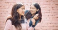 Portrait of two young pretty Indian girls posing against a brick wall background Royalty Free Stock Photo