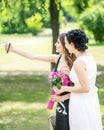 Portrait of two young pretty women friends taking selfie in green summer park. Pretty females bride and bridesmaid taking photogra Royalty Free Stock Photo