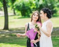 Portrait of two young pretty women friends talking in green summer park. Pretty females bride and bridesmaid smiling and chatting Royalty Free Stock Photo