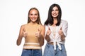 Portrait of two young women friends gesturing thumbs up over white background Royalty Free Stock Photo