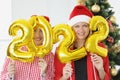 Portrait of two young women holding numbers 2022 in hands against of New Year tree Royalty Free Stock Photo