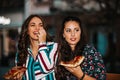 Portrait of two young women laughing and eating pizza outdoors, having fun together Royalty Free Stock Photo
