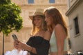 Portrait of two young women with shopping bags in hand looking at the cell phone of one of them smiling Royalty Free Stock Photo