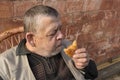 Portrait of Ukainian senior Sitting agaist brick wall and eating patty Royalty Free Stock Photo