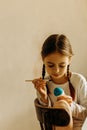 Cute little child girl painting with blue and yellow colors Easter eggs. Hands of a girl with a easter egg. Close-up