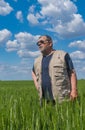 Portrait of Ukrainian senior farmer standing inside unripe crops field