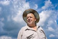 Portrait of Ukrainian senior farmer in straw hat against blue cloudy sky