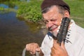 Portrait of Ukrainian senior squinted sitting on a riverside