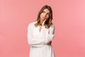 Portrait of uneasy thoughtful serious-looking blond girl, wear white dress, look up, lean head on palm and frowning as Royalty Free Stock Photo