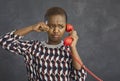 Portrait of unhappy capricious african american woman crying while talking on landline retro phone.