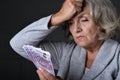 Portrait of unhappy elderly woman with euros