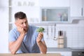 Portrait of unhappy man looking at broccoli in