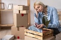 Portrait of unhappy modern woman in t-shirt near cardboard box with a broken dish on background Royalty Free Stock Photo