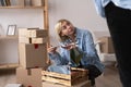 Portrait of unhappy modern woman in t-shirt near cardboard box with a broken dish Royalty Free Stock Photo