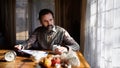 Portrait of unhappy poor mature man reading newspapers indoors at home, poverty concept.