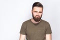 Portrait of unhappy sad bearded man with dark green t shirt against light gray background. Royalty Free Stock Photo