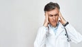 Portrait of unhappy stressed male doctor in medical uniform feeling depressed, touching head with hands while standing Royalty Free Stock Photo