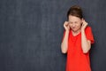 Portrait of unhappy young woman plugging her ears with fingers