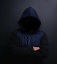 Danger lurks within the dark. Portrait of an unrecognisable hooded man posing against a dark background. Royalty Free Stock Photo