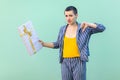 Portrait of unsatisfied with short hair young woman in striped suit standing, showing dislike gesture to her present box, looking