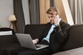 Portrait of unsatisfied young company director with trendy haircut and beard working with laptop computer, talking on