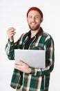 Portrait of unshaved man holding silver laptop and credit card, while standing isolated over white background Royalty Free Stock Photo