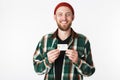 Portrait of unshaved man laughing and holding credit card, while standing isolated over white background Royalty Free Stock Photo