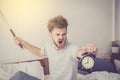 Portrait upset angry with baseball hit young man screaming at alarm clock on bedroom. Royalty Free Stock Photo