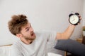 Portrait upset angry young man screaming at alarm clock Royalty Free Stock Photo