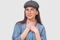 Portrait of upset brunette girl having cold or flu, feeling bad, standing against gray background. Young woman having a sore Royalty Free Stock Photo