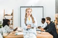 portrait of upset businesswoman with arms crossed looking at camera and colleagues working behind