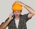 Portrait of upset construction worker or stressed contractor man in builder hat talking on mobile phone unhappy in stress messing Royalty Free Stock Photo