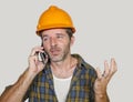 Portrait of upset construction worker or stressed contractor man in builder hat talking on mobile phone unhappy in stress messing Royalty Free Stock Photo