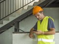 Portrait of upset construction worker or stressed contractor man in hardhat and vest checking on mobile phone unhappy in stress Royalty Free Stock Photo