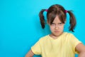 Portrait of upset displeased sulking angry little toddler girl over blue background Royalty Free Stock Photo