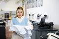 Portrait of an upset female employee of printing house with torn piece of paper in her hands