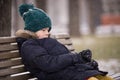 Portrait of upset kid boy sitting on a wooden bench in the park on cold day Royalty Free Stock Photo