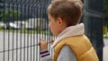 Portrait of upset little boy feeling alone looking through metal fence. Child depression, problems with bullying, victim in school Royalty Free Stock Photo