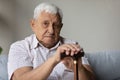 Portrait of upset old pensioner with wooden cane in hands. Royalty Free Stock Photo