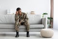 Upset Pensive Black Military Woman In Uniform Sitting On Couch At Home