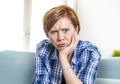 Portrait of upset and pretty red hair woman around 30 years old at home living room looking sad and worried in sadness emotion fac