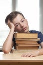 Portrait of upset schoolboy looking at textbook with homework