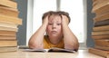 Portrait of upset schoolboy looking at textbook with homework