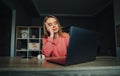 Portrait of upset woman in pink sweater working on laptop at home at work and looking wearily at computer screen with head resting Royalty Free Stock Photo