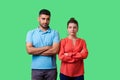 Portrait of upset young couple in casual wear standing together looking resentful. isolated on green background