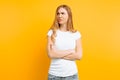 Portrait of an upset young girl standing with folded arms and offended face, on yellow background Royalty Free Stock Photo